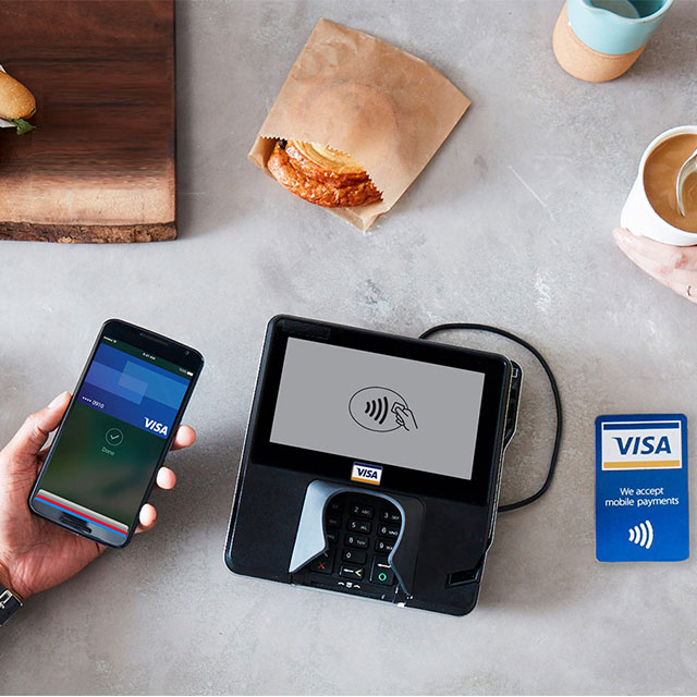 Paying for coffee shop items with Apple Pay at a contactless-enabled terminal.